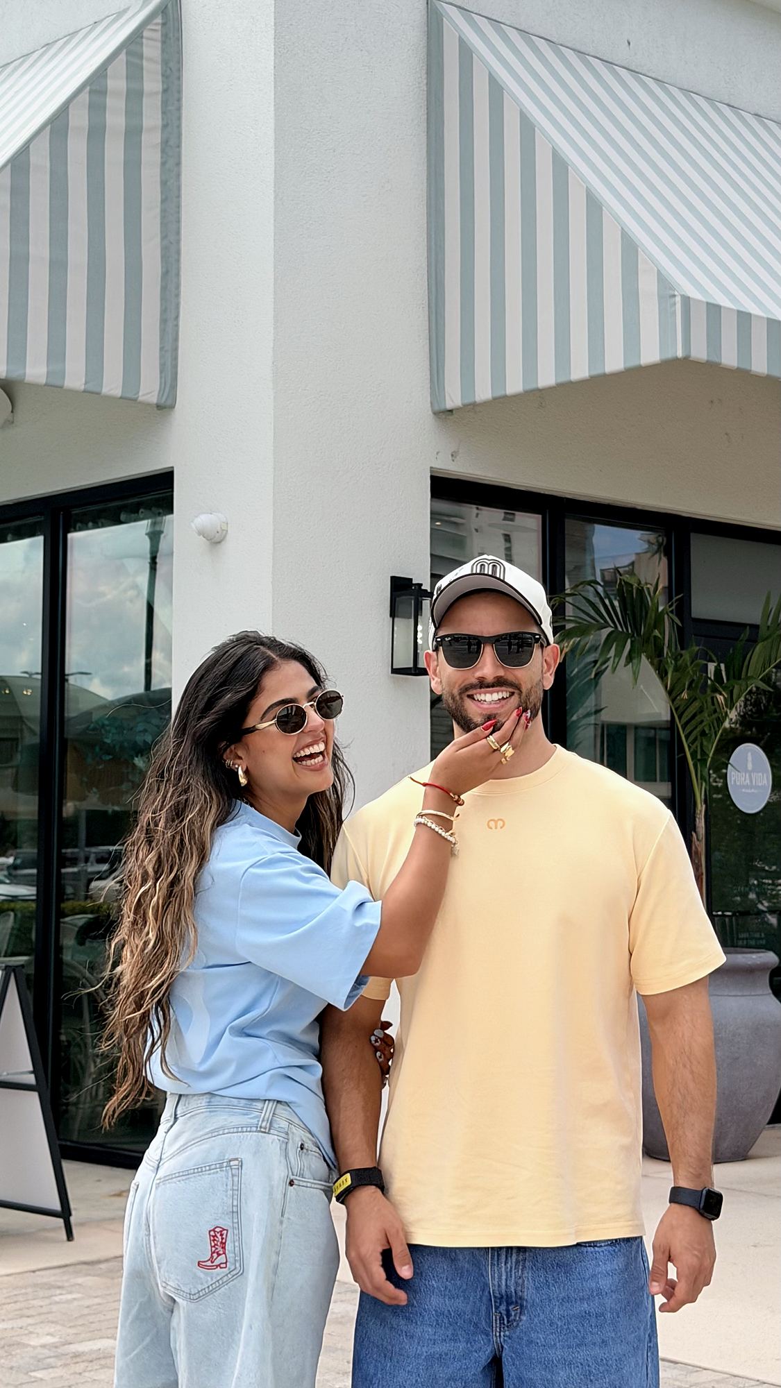 Two friends in Mentafit unisex oversized shirts, Ochre and Dusty Blue, laughing on a sunny street